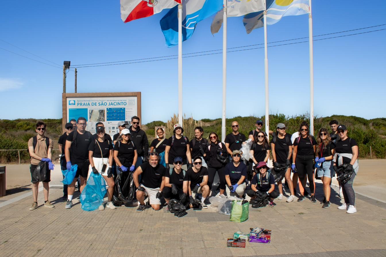 Amplio grupo de voluntarios junto a las banderas de Praia de São Jacinto, con bolsas de basura recogida