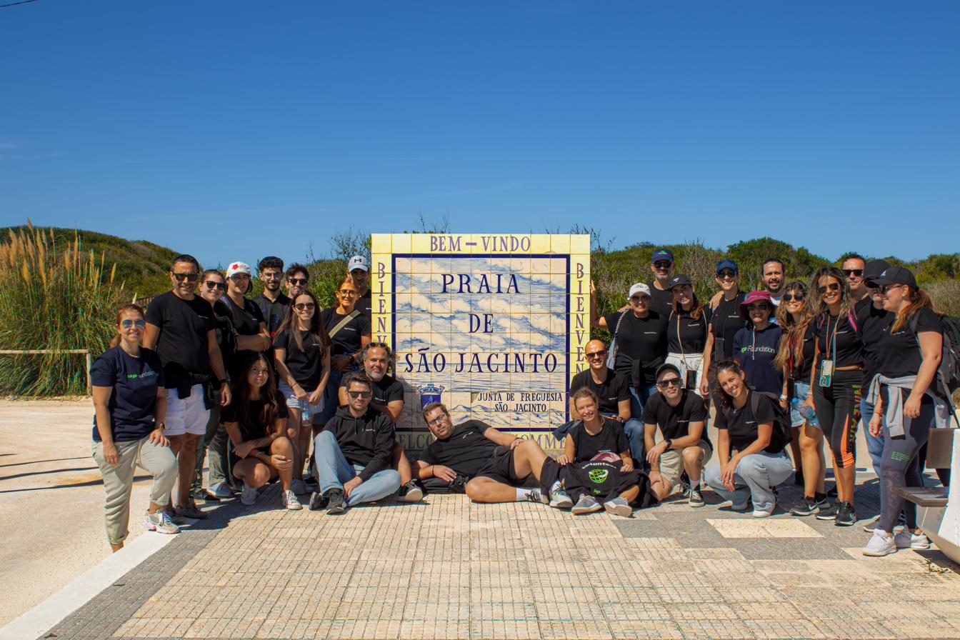 Amplio grupo de voluntarios junto al cartel de Praia de São Jacinto