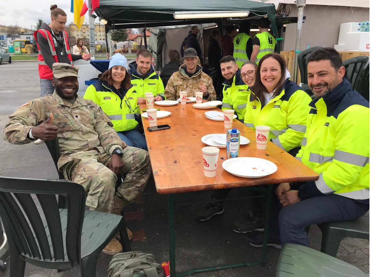 Voluntarios y militares reunidos junto a una tienda de ayuda humanitaria en Przemyśl, Polonia
